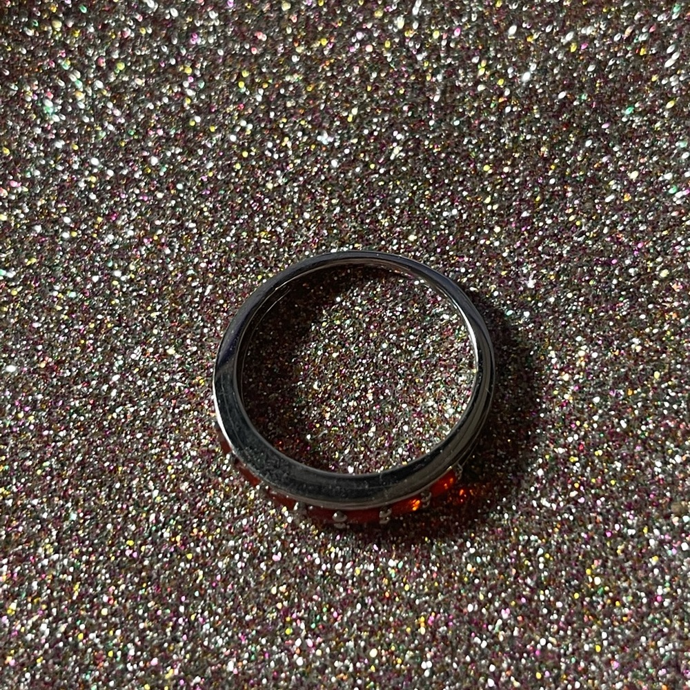 Sterling silver ring with orange stones on the front half.